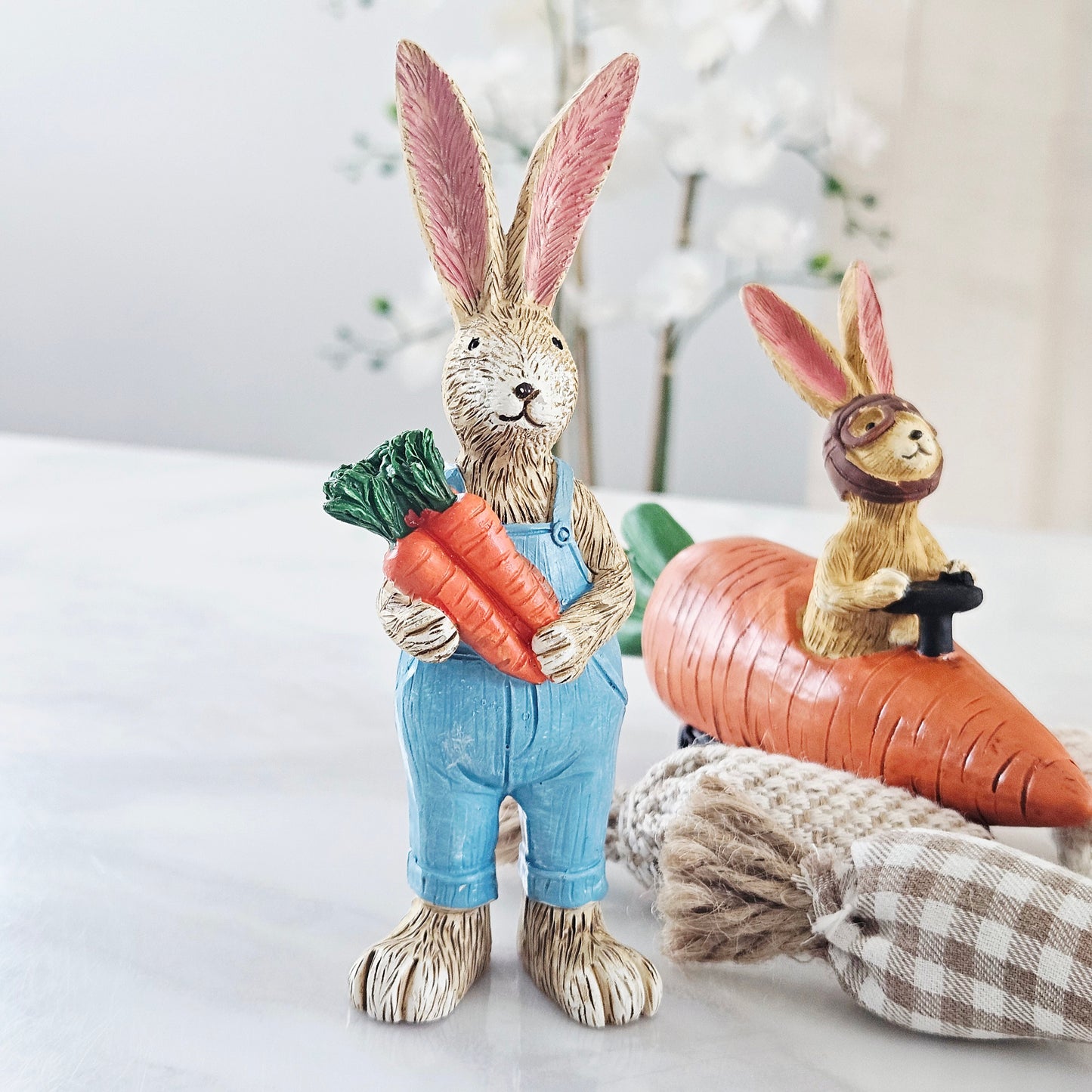 Decorative rabbit figurine holding a carrot bunch dressed in blue dungarees 