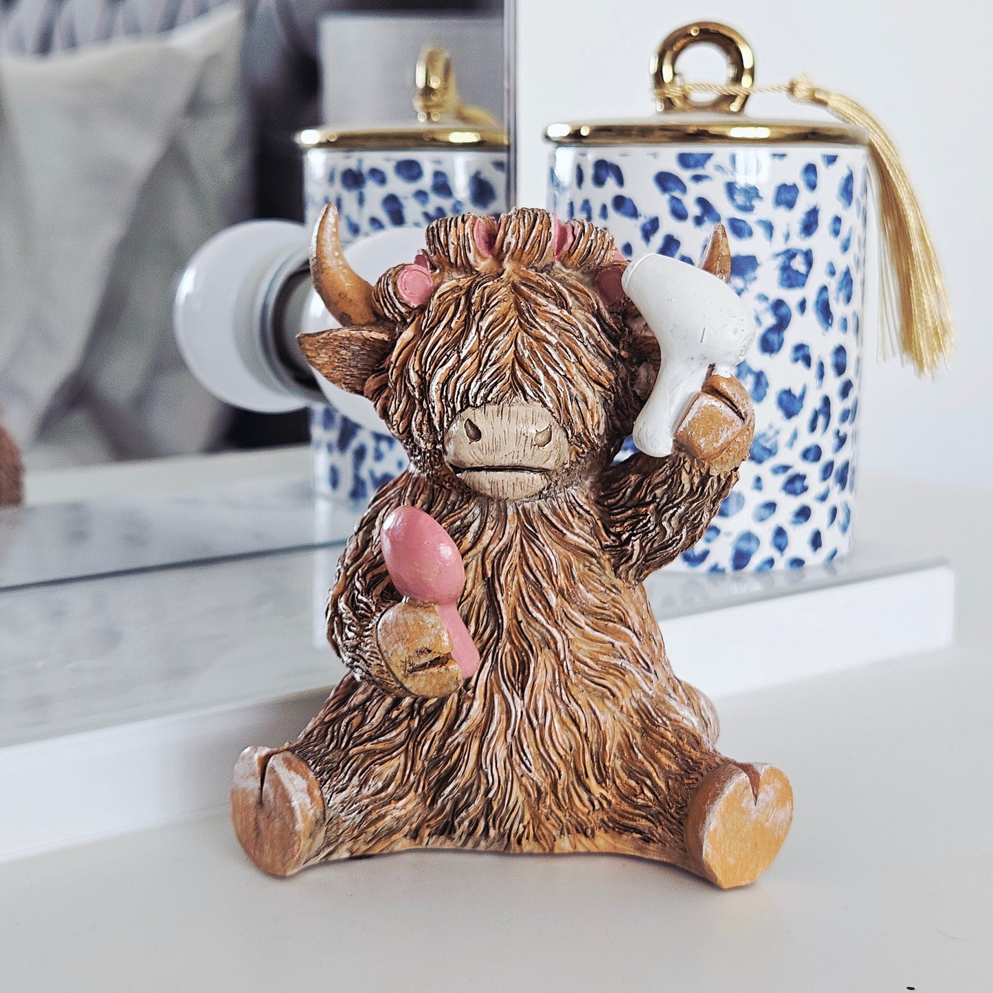 highland cow ornament hairdo with rollers in hair holding hairdryer and brush