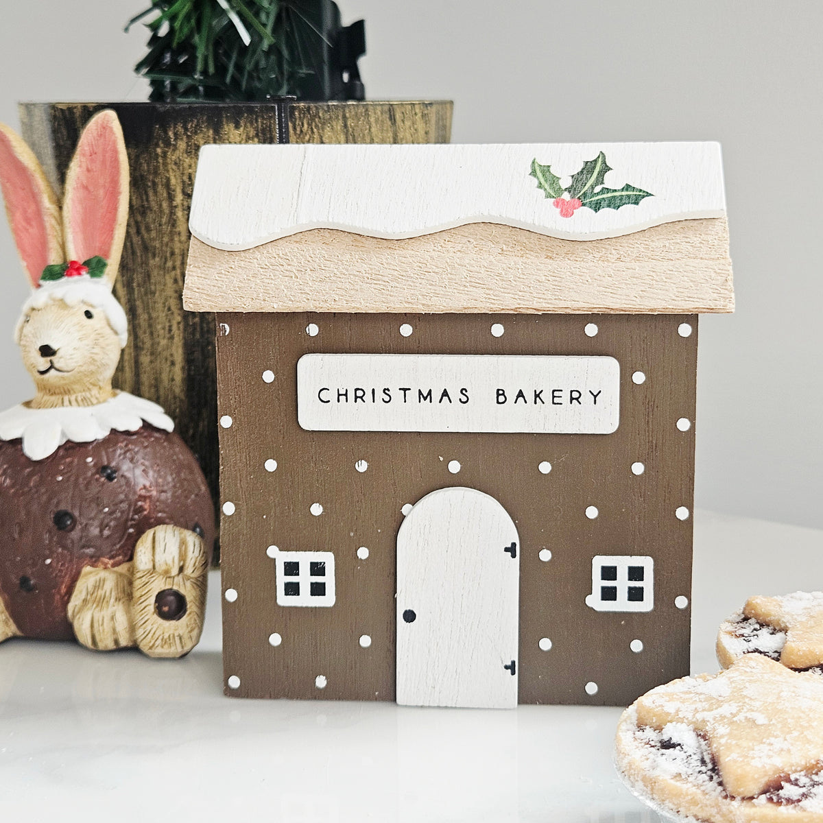 A decorative wooden house sign with 'CHRISTMAS BAKERY' on the front
