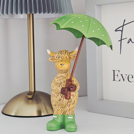 highland cow ornament 16cm holding a green spotty umbrella with green wellies