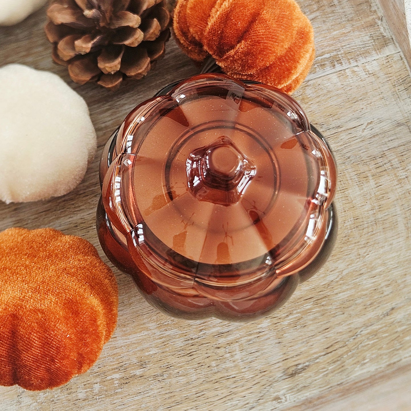 A small amber-brown glass pumpkin shaped candle with a scalloped rim and lid, for autumn scent 