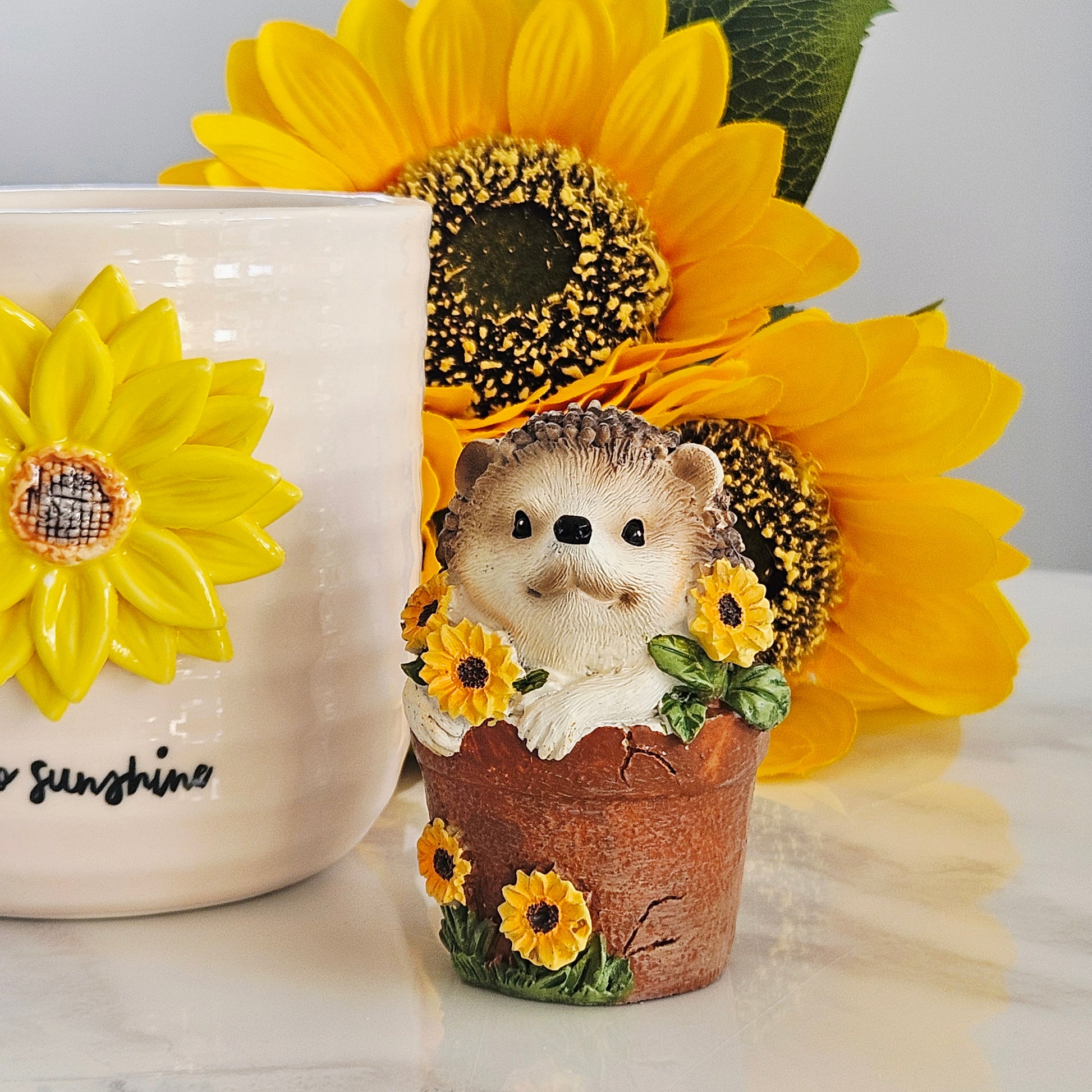 decorative hedgehog small ornament inside a plant pot with sunflowers