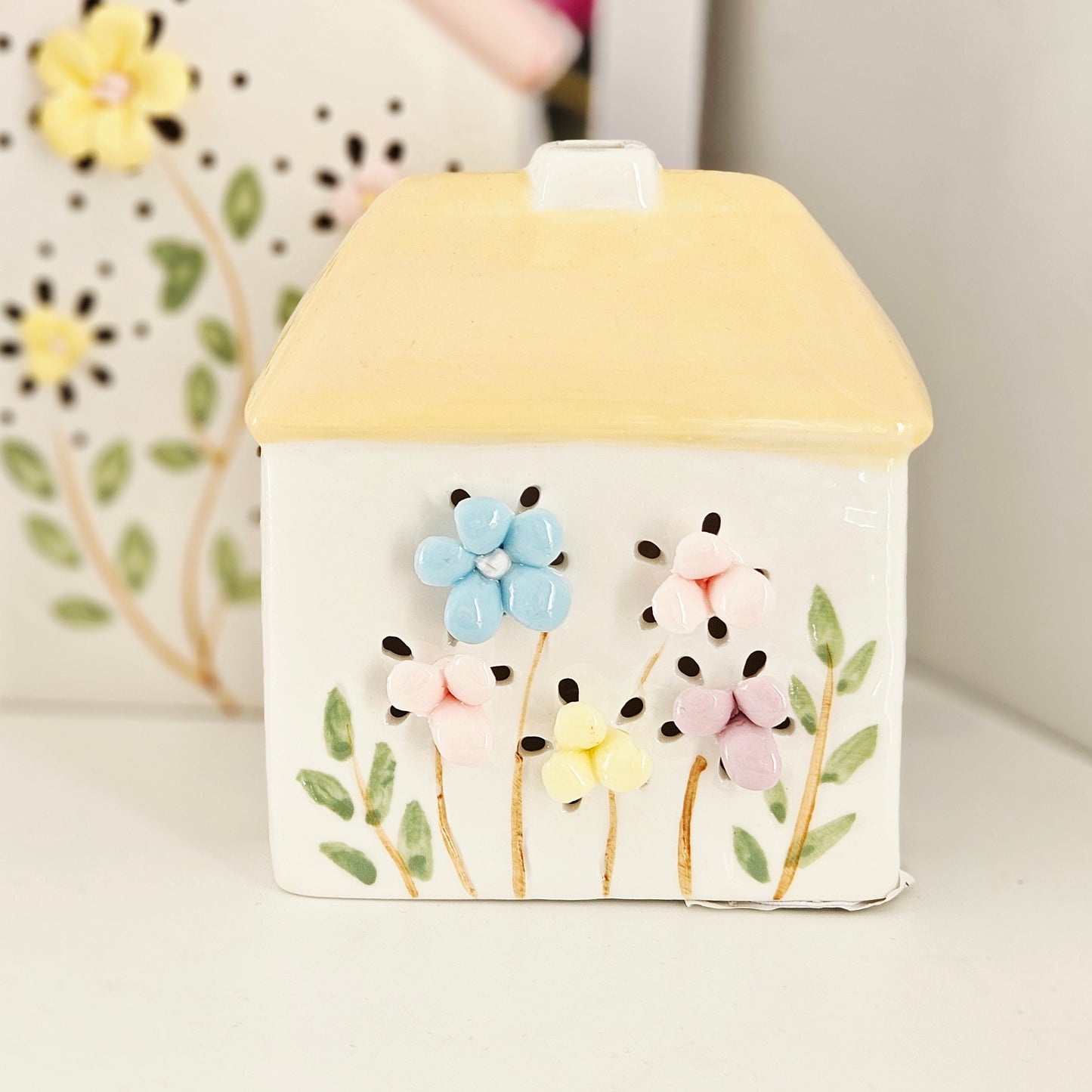 Decorative ceramic house with floral design and yellow roof