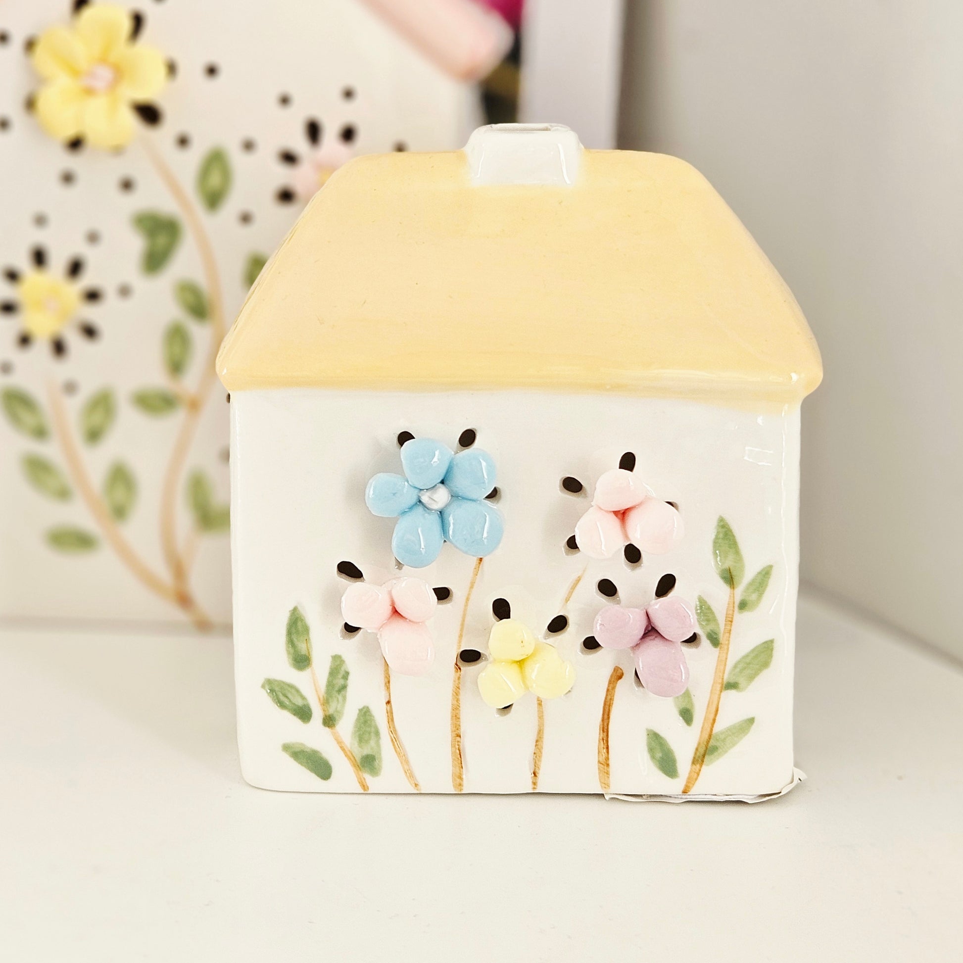 Decorative ceramic house with floral design and yellow roof