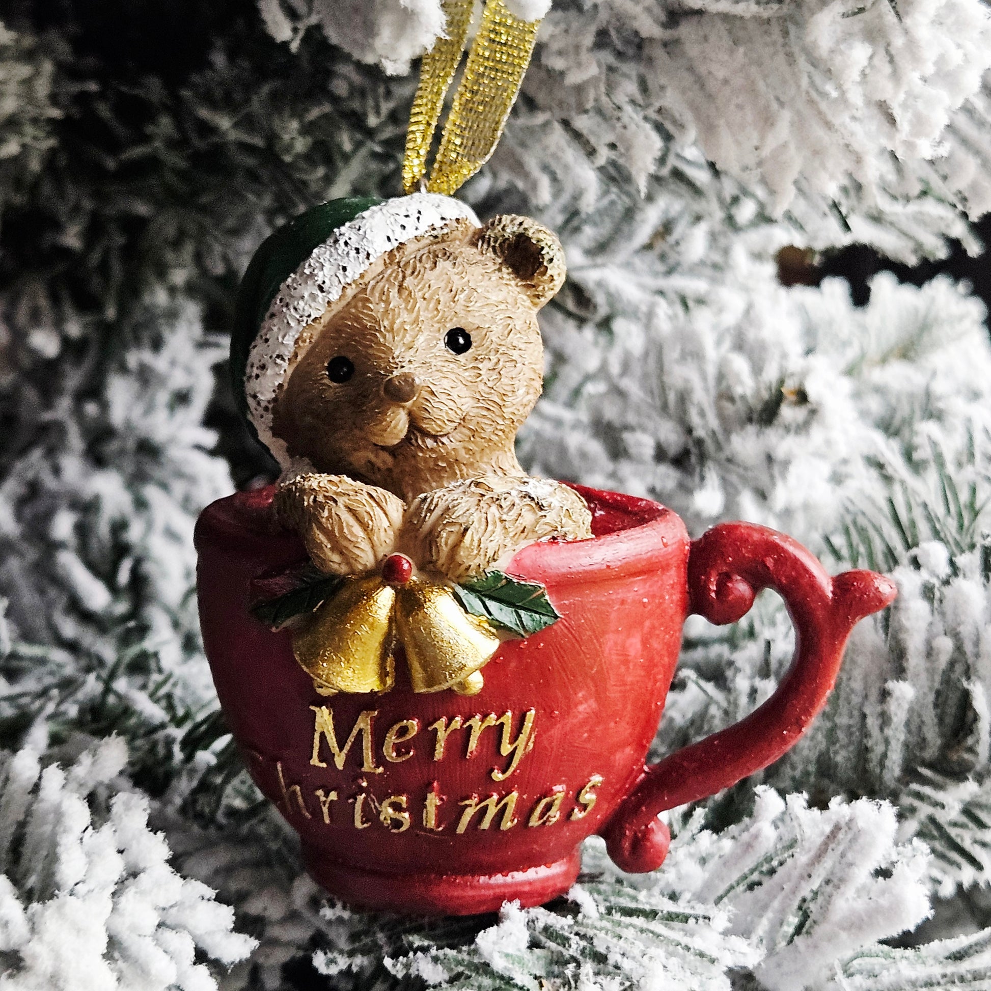 Christmas ornament of a teddy bear in a red mug with 'Merry Christmas' text and bells