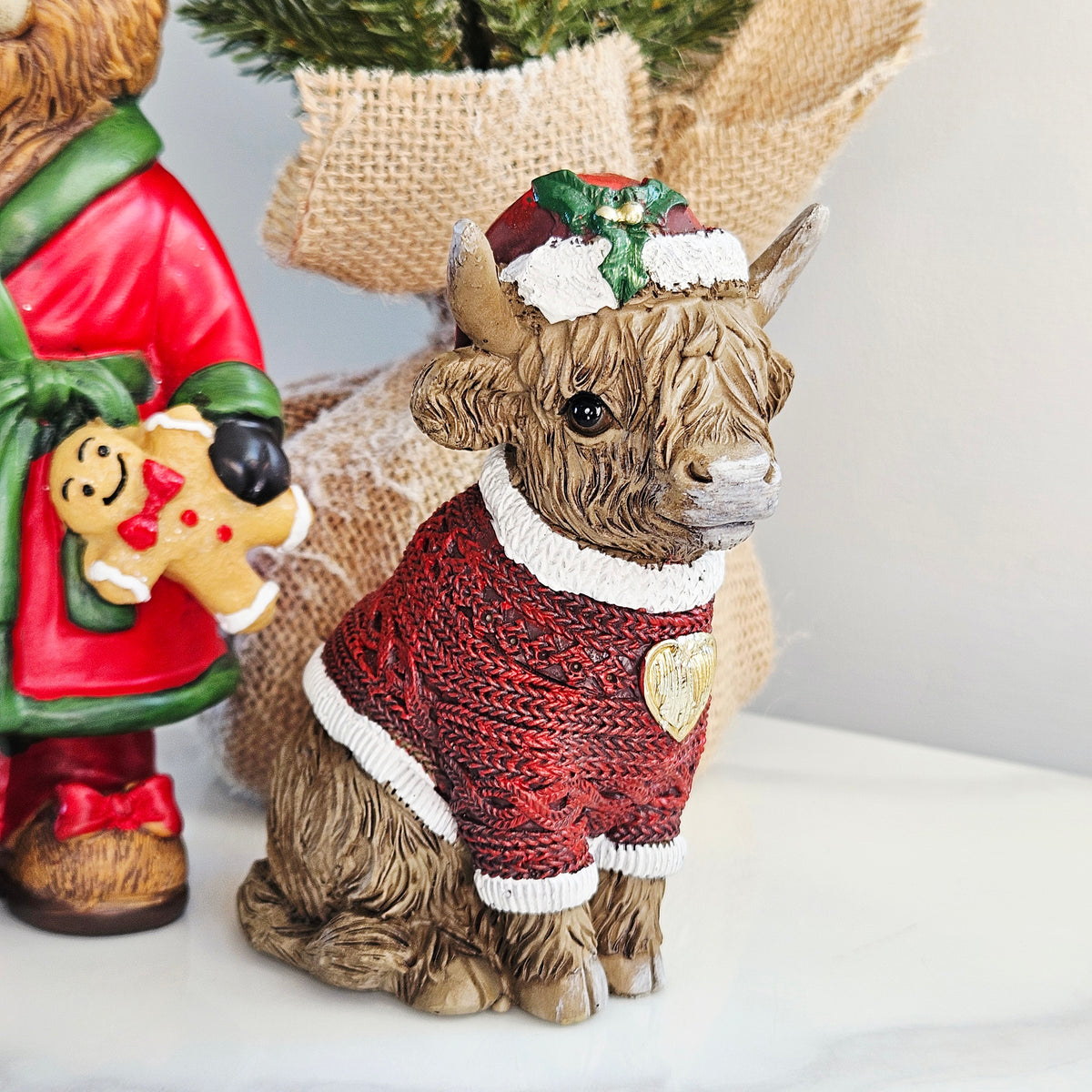 Sitting Highland Cow Christmas Figurine wearing a Santa hat and red Christmas jumper