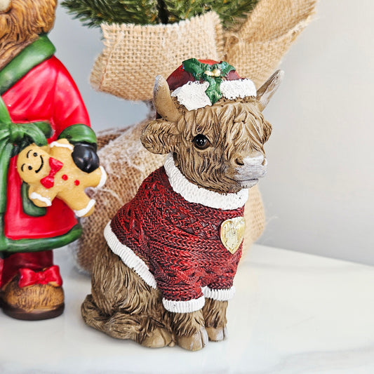 Sitting Highland Cow Christmas Figurine wearing a Santa hat and red Christmas jumper