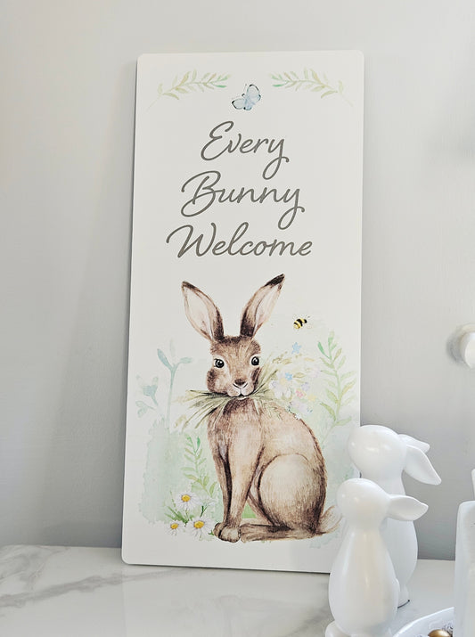 Decorative sign with a rabbit illustration and 'Every Bunny Welcome' text on a white surface.