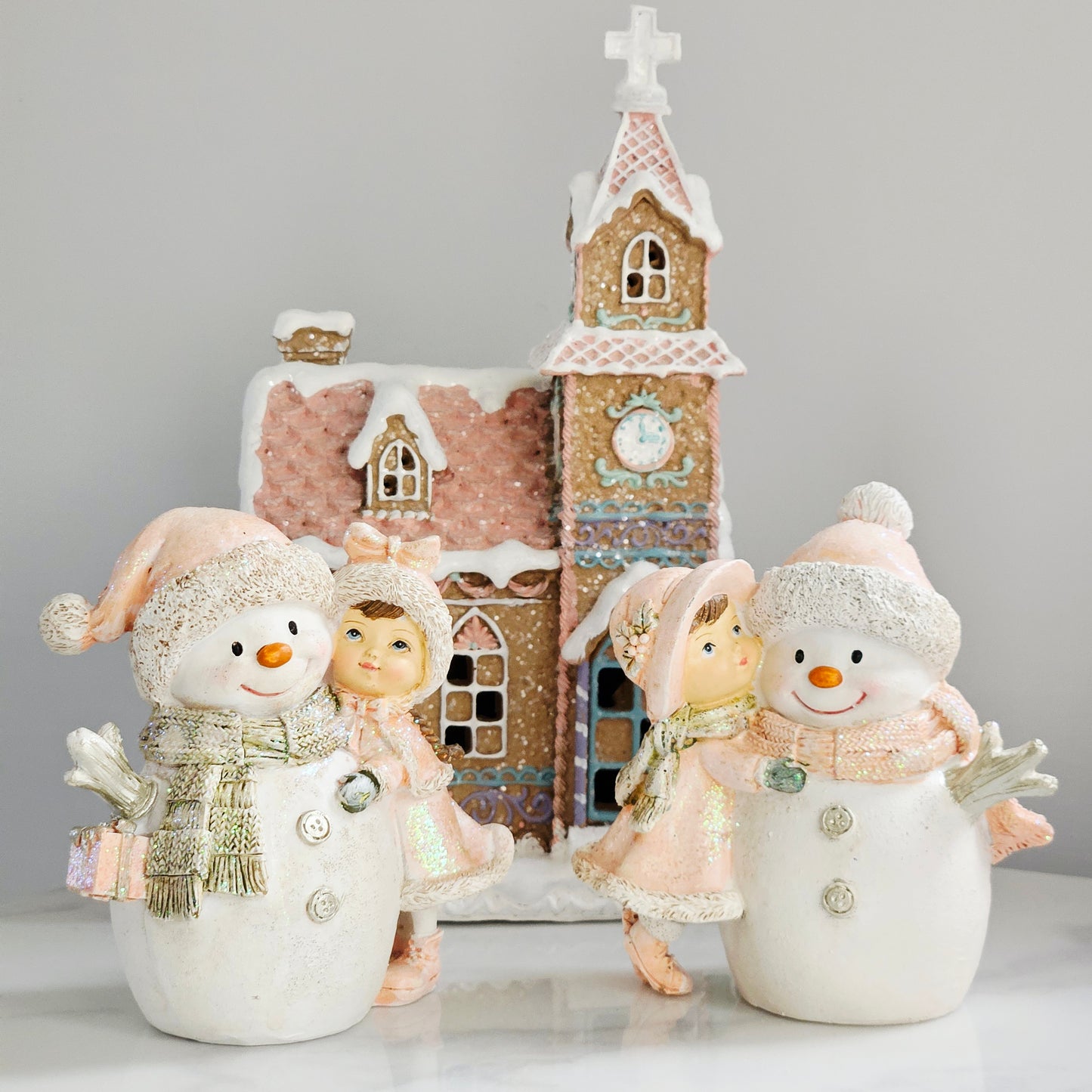 Decorative snowman figurines with sweet girl wearing pink hats and scarves hugging