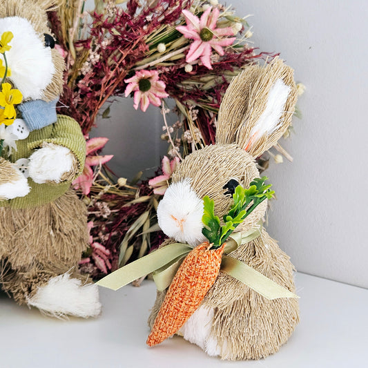 natural materials bunny holding a carrot decoration with a green bow around neck