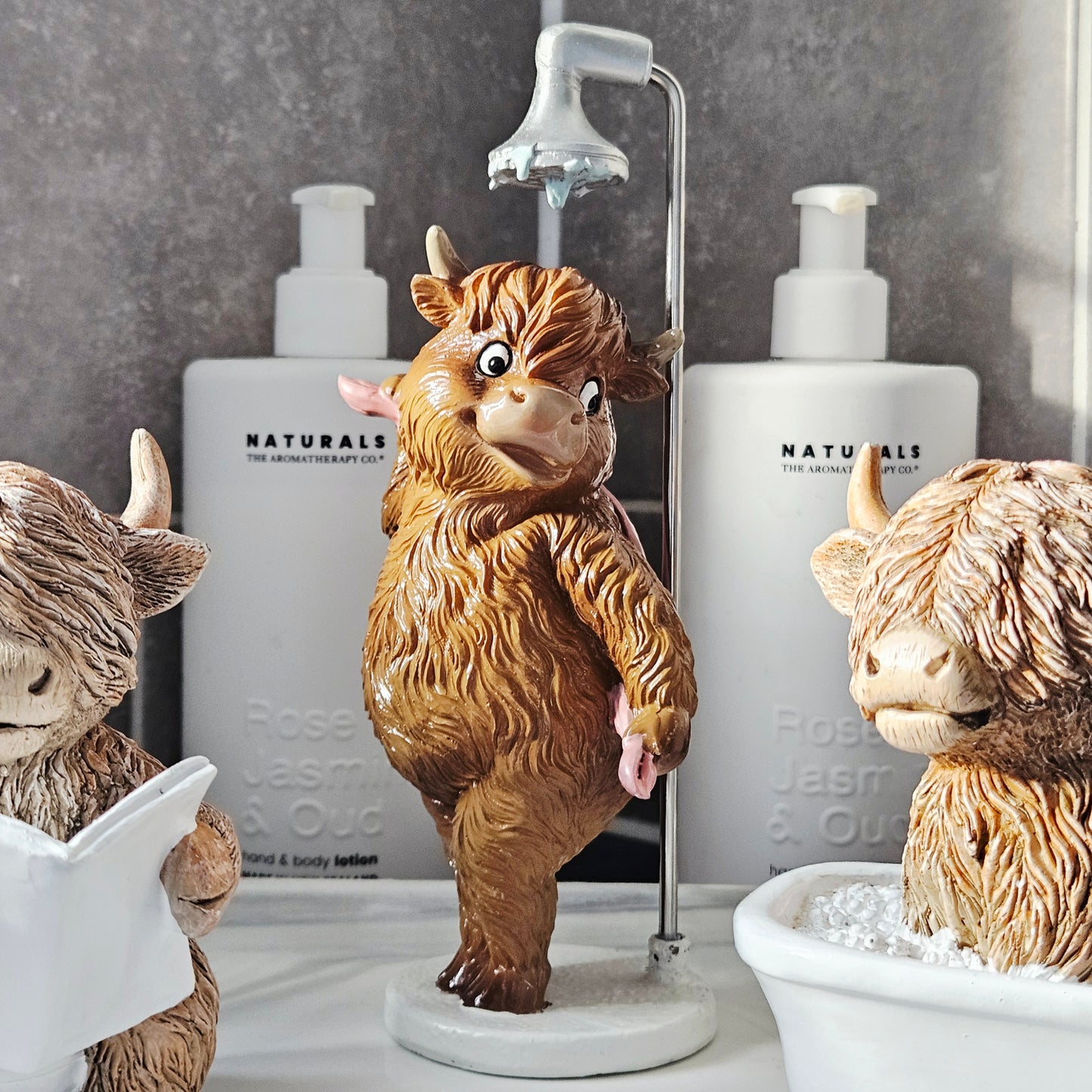 highland cow in the shower with pink bath towel and shower head