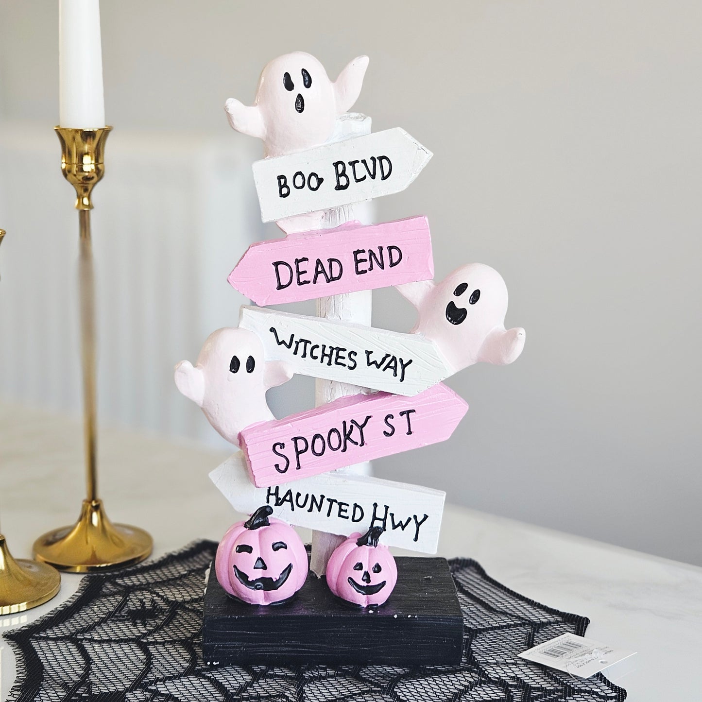 Halloween tabletop decor signpost with ghost figures and directional arrows reading BOO BLVD, DEAD END, WITCHES WAY, SPOOKY ST, and HAUNTED HWY, plus two small jack-o'-lanterns on a black base