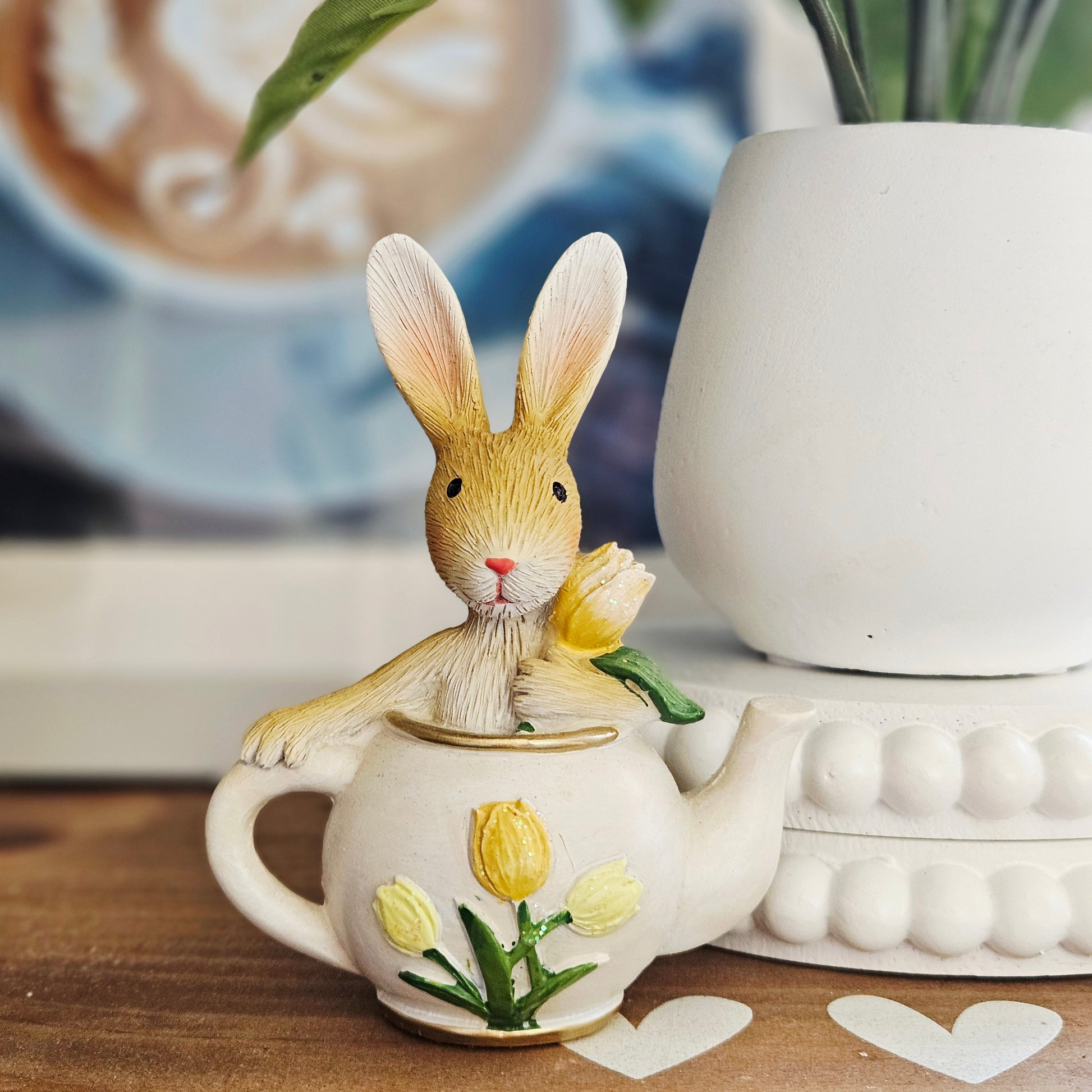 Decorative teapot with a rabbit figurine holding a tulip