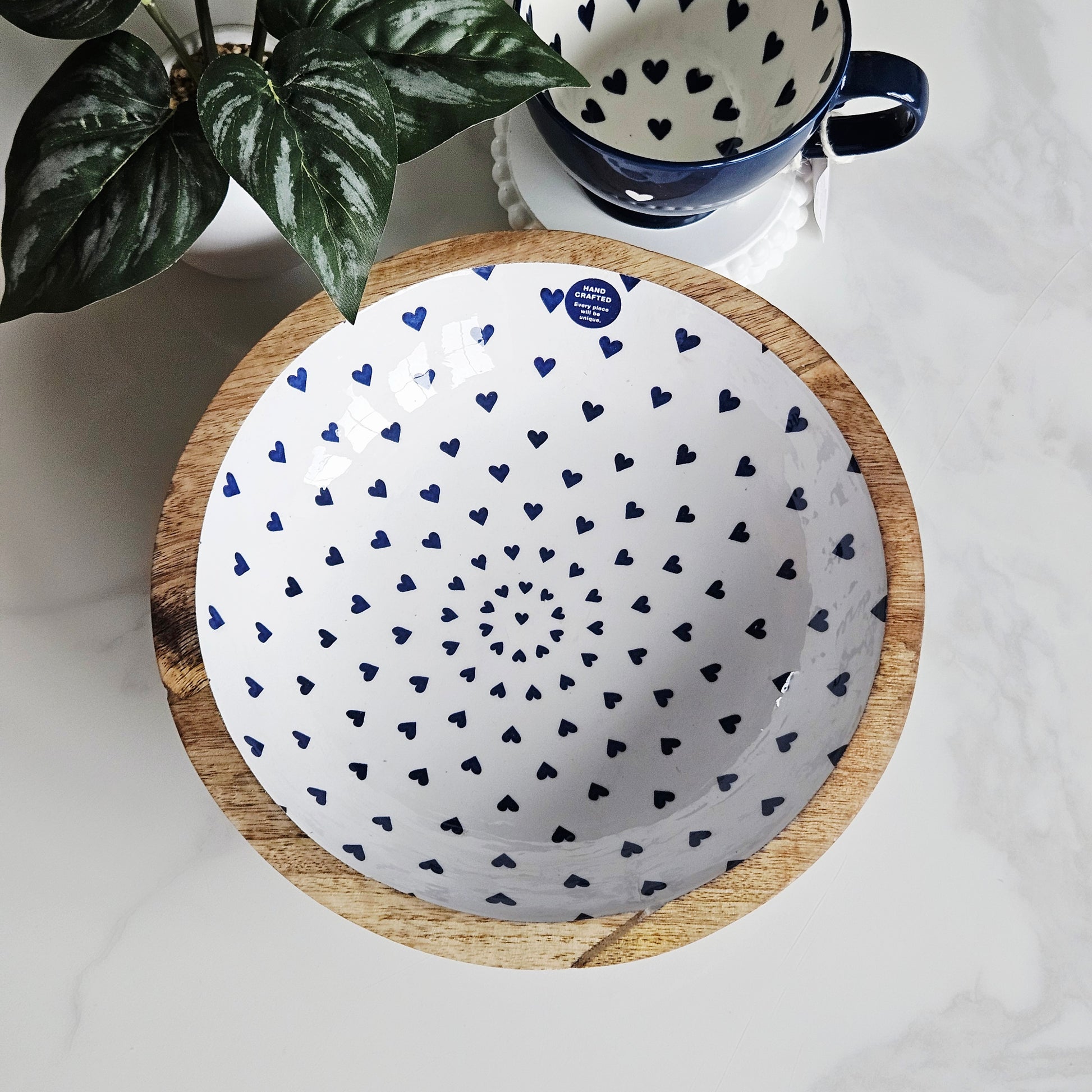 Wooden mango wood bowl with a white interior featuring blue heart patterns on a white background