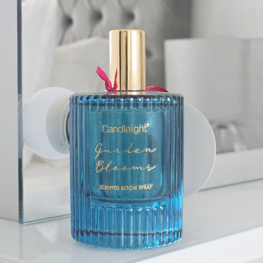 Blue scented room spray bottle with floral design and 'Candlelight Garden Blooms' label 