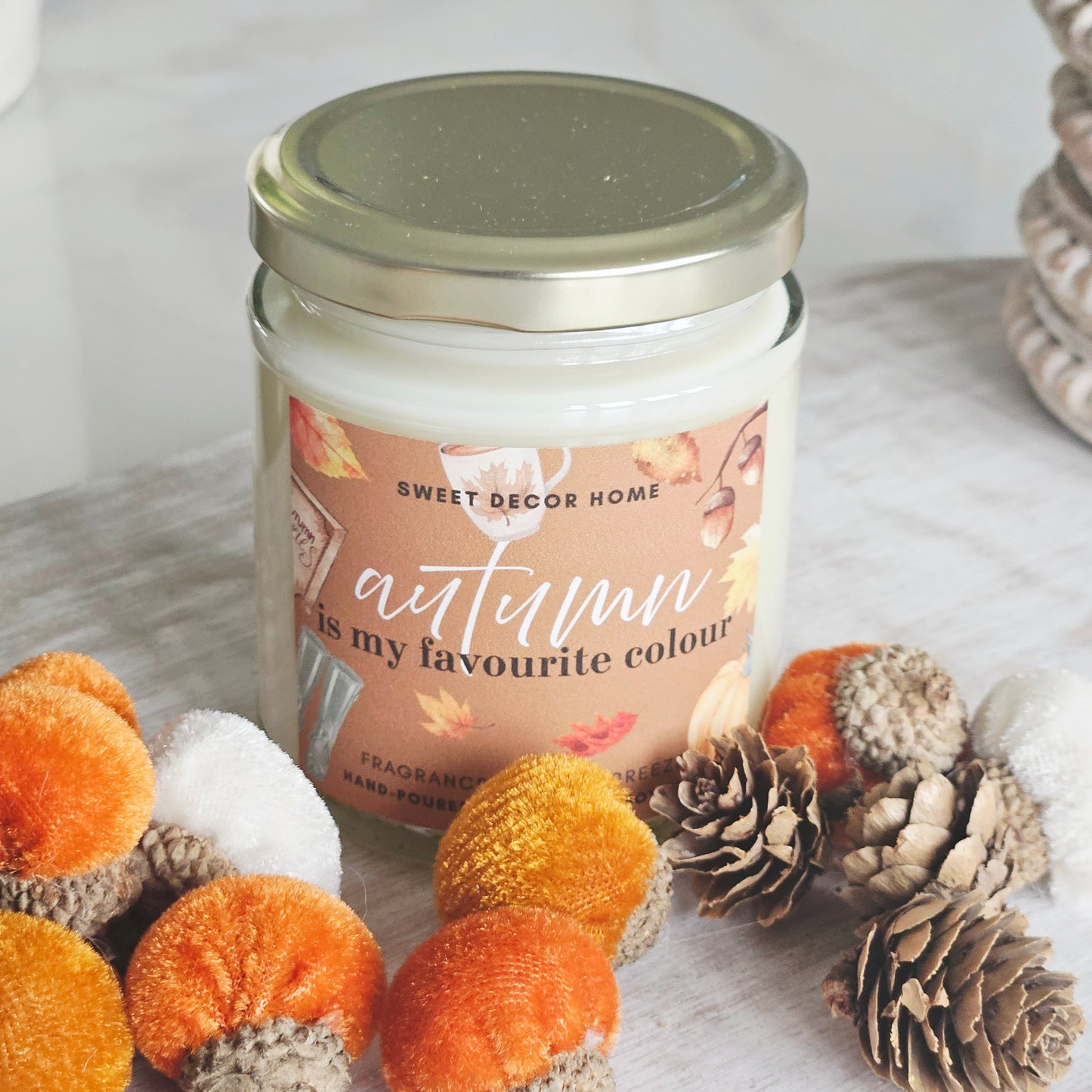 A jar candle from Sweet Decor Home with an autumn-themed label reading 'autumn is my favourite colour'. Autumn breeze