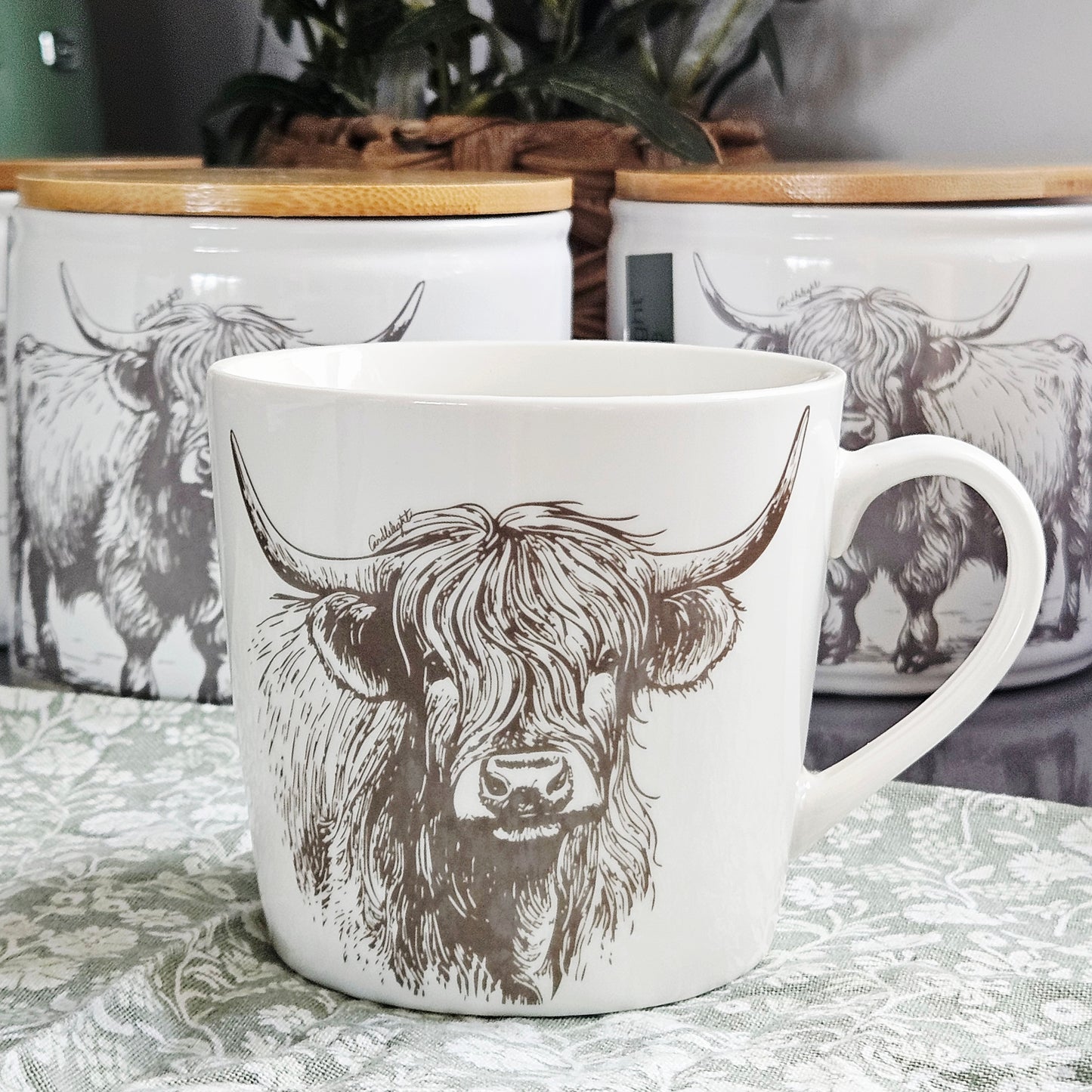 White conical ceramic mug with black illustrated Highland cow design