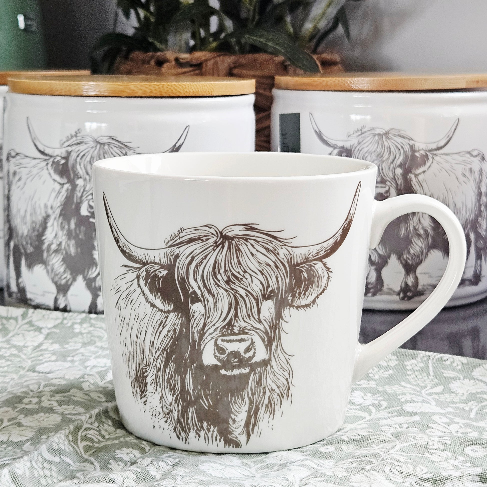 White conical ceramic mug with black illustrated Highland cow design