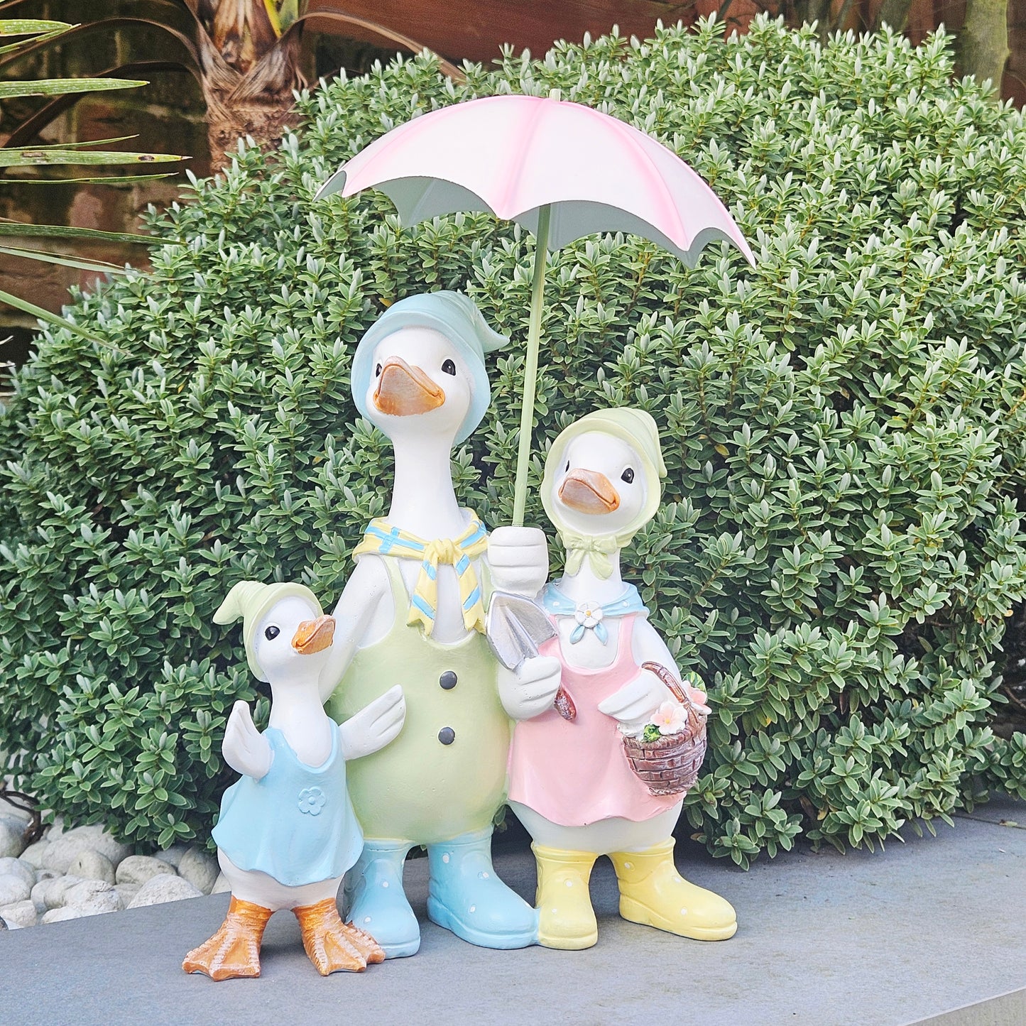 Decorative figurines family of ducks with a pink umbrella dressed in pastel colours 