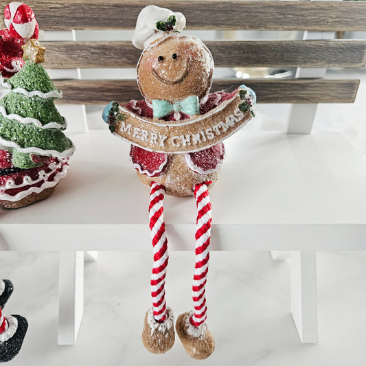 Decorative gingerbread man with candy cane legs holding a 'Merry Christmas' sign 