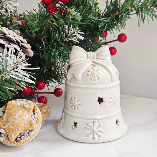 A white ceramic led Christmas bell-shaped ornament with embossed snowflakes and star cutouts