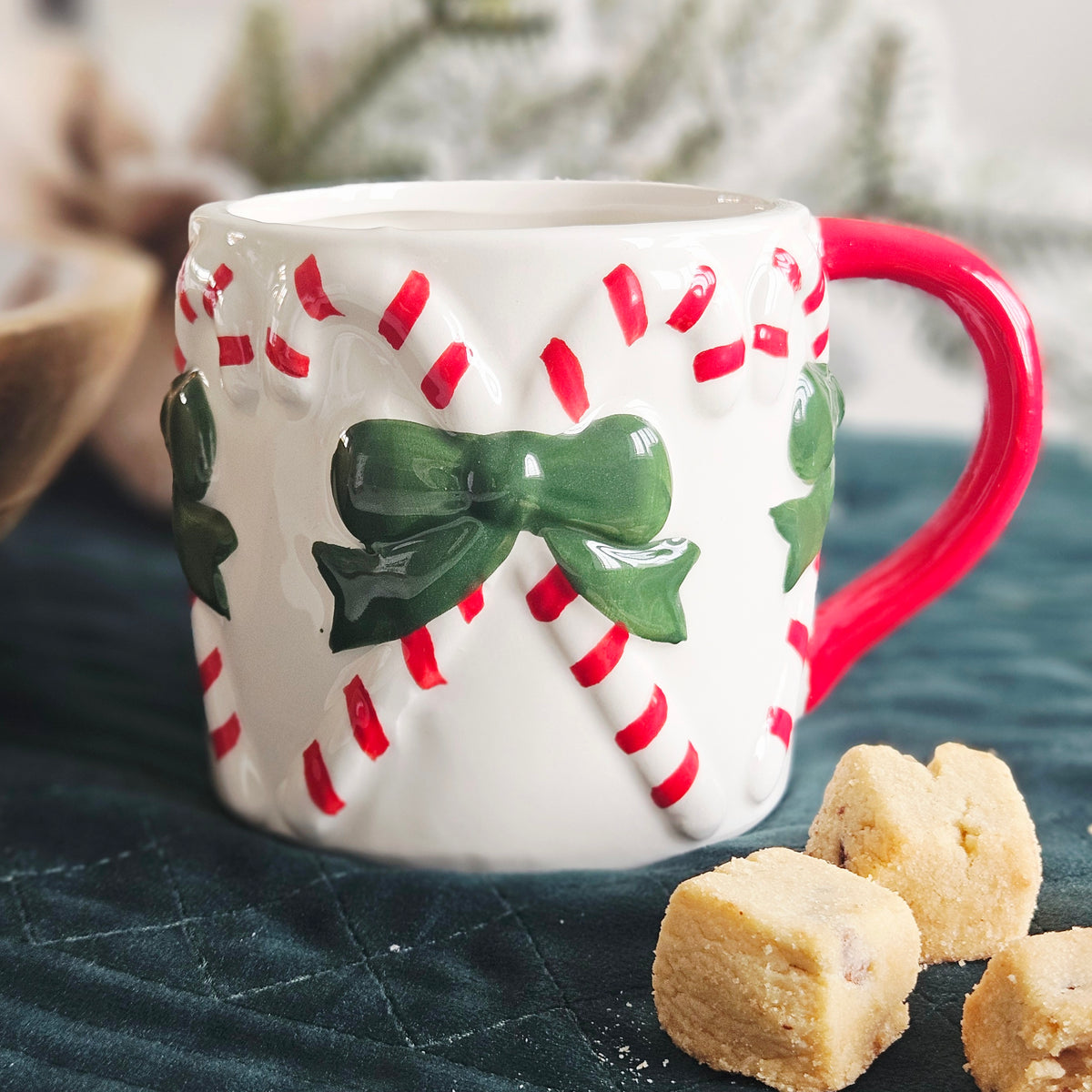 A white ceramic mug decorated with 3D candy canes and green bows