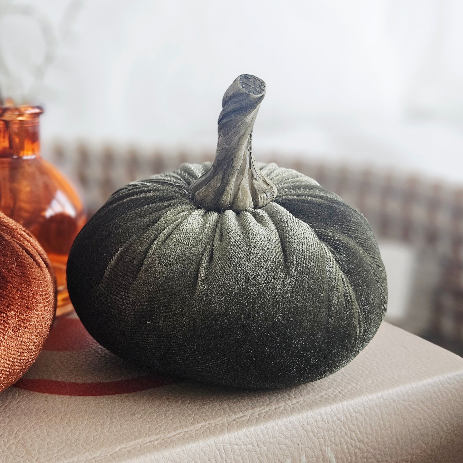 A dark olive green small velvet fabric pumpkin decoration with a textured stem, 
