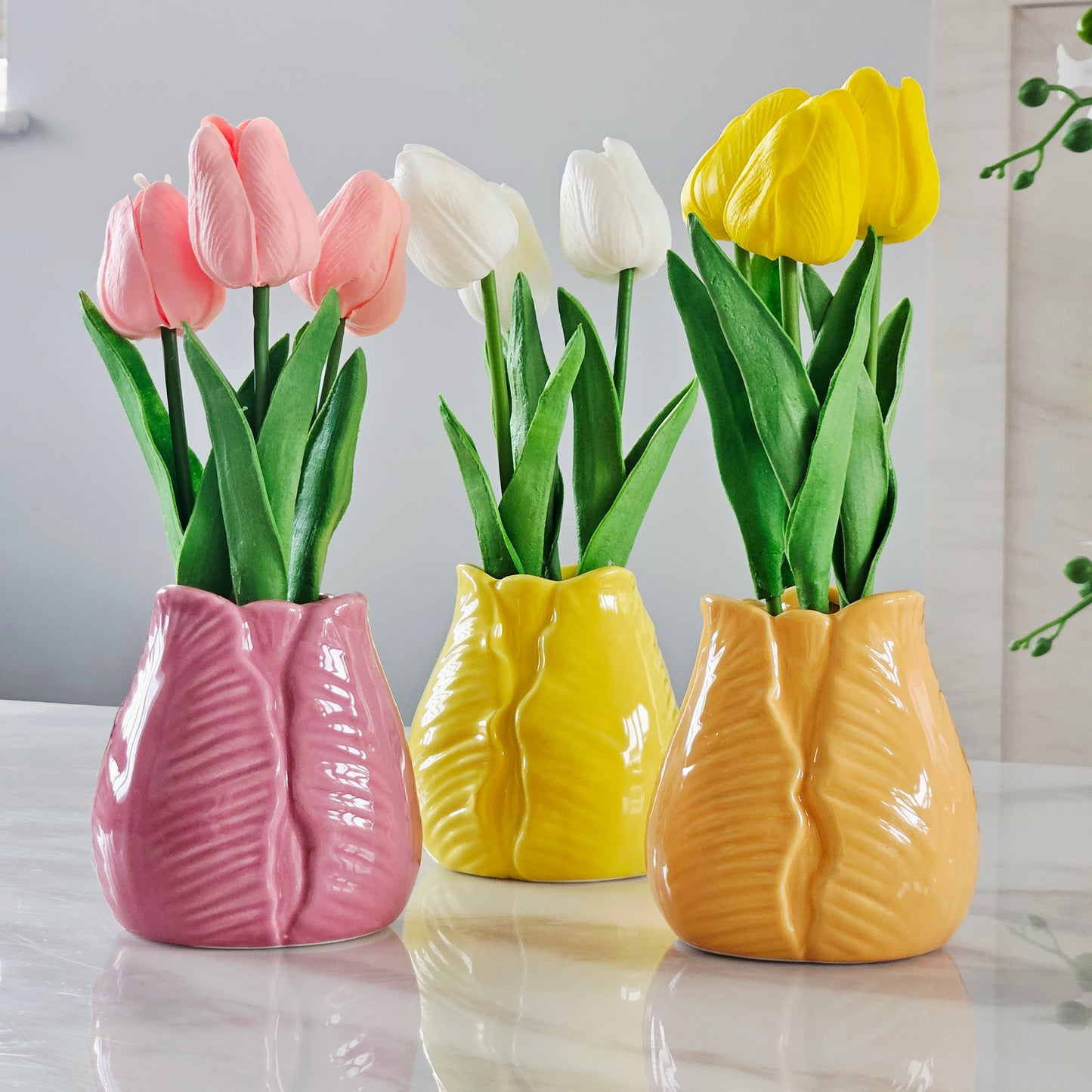 Three colorful tulip vases in pink, yellow,  and orange white, yellow and pink tulips 