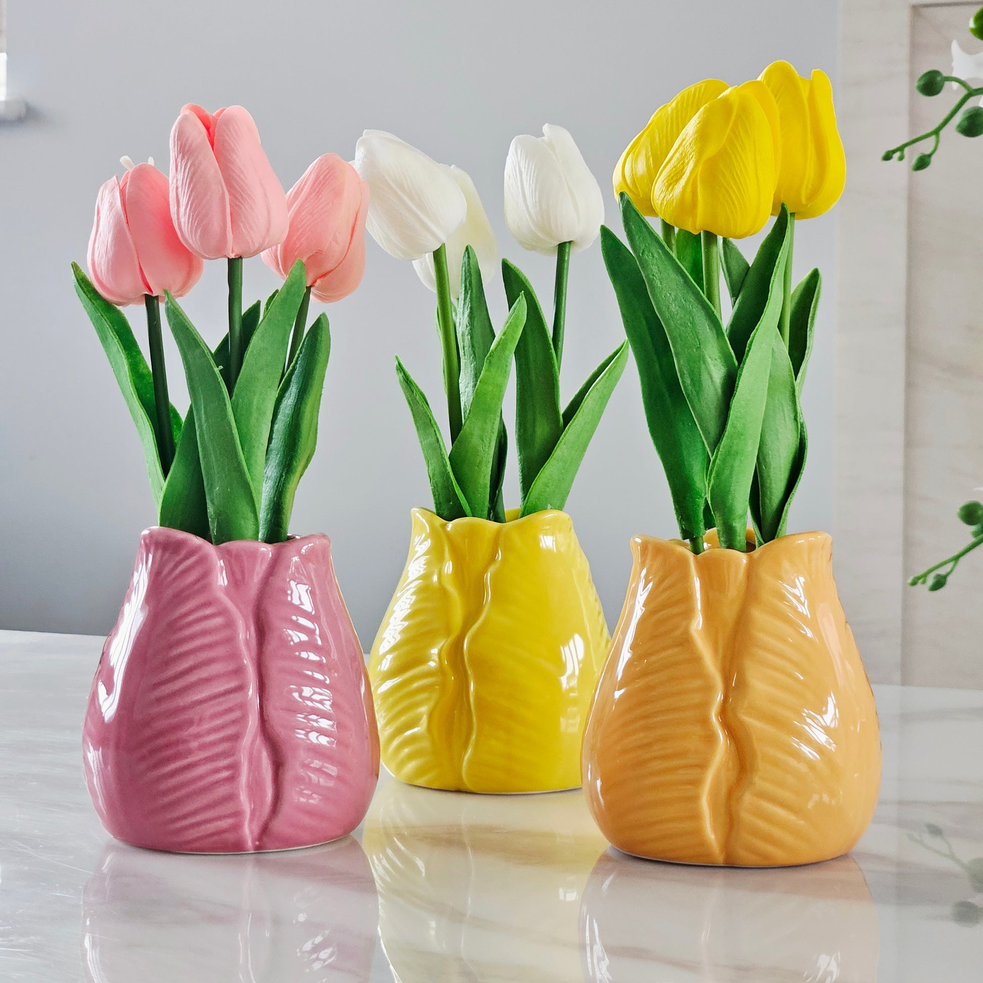 Three colorful tulip vases in pink, yellow,  and orange white, yellow and pink tulips 