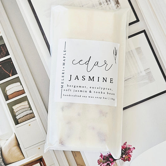 Packaged wax melt snap bar labeled 'cedar jasmine' next to an unwrapped soap bar with visible ingredients.