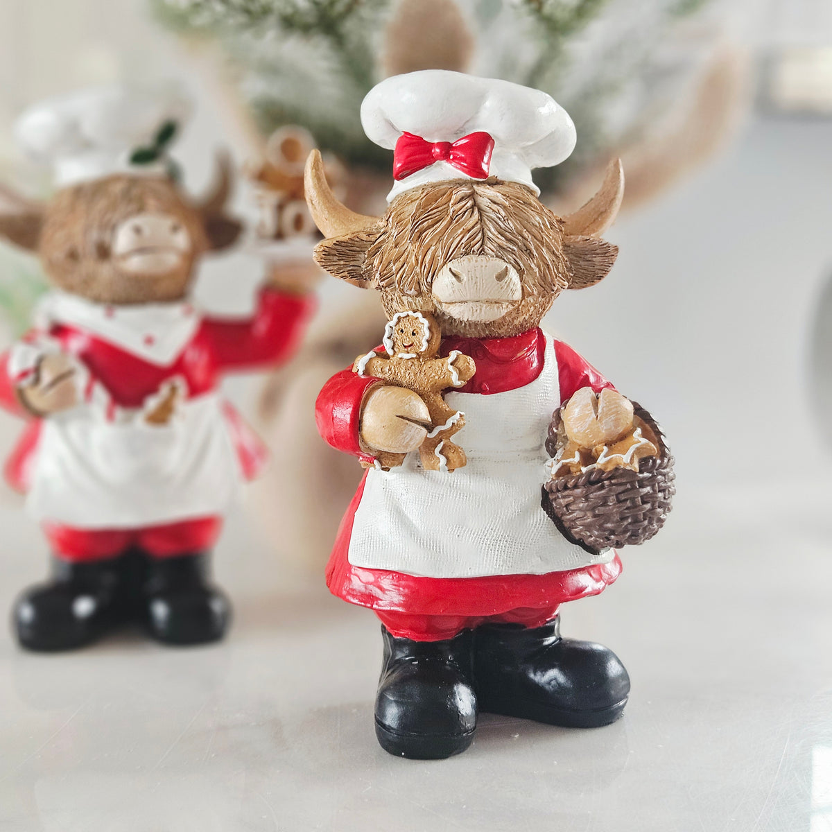 christmas highland cow chef with hat and red bow holding a gingerbread 