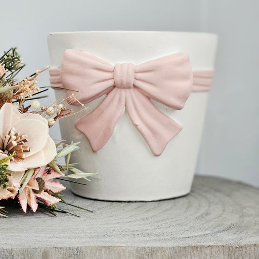 white plant pot with overside pink bow wrapped around it 