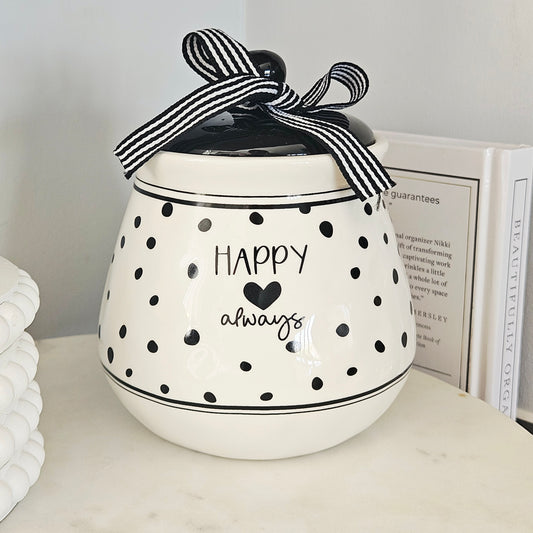 White ceramic jar with black polka dots and text, tied with a black and white striped ribbon, happy always text