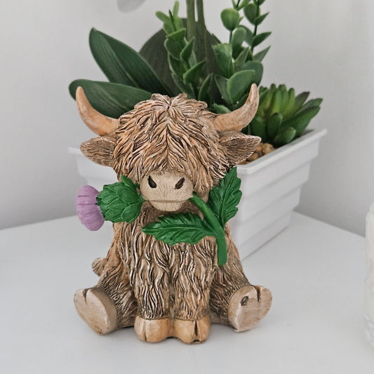 ornament of a Highland cow holding a flower thistle in its mouth 
