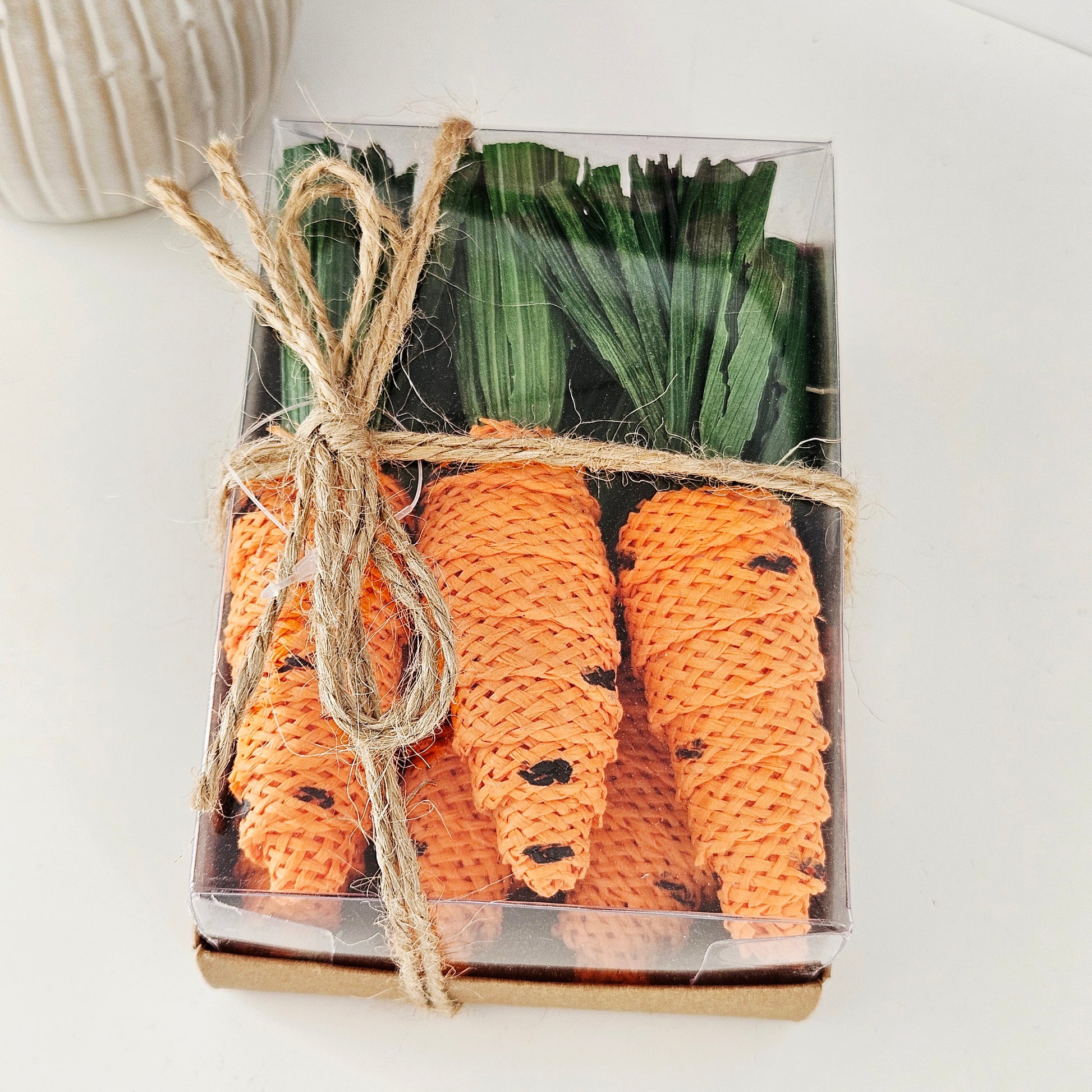 Carrot-shaped decorative pieces x6 in a clear box with a brown cardboard base 