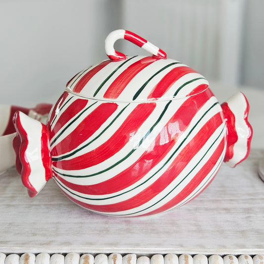 A glossy ceramic candy- sweet shaped lidded storage jar ceramic with red and white diagonal stripes, green accent lines, and a candy cane handle on top