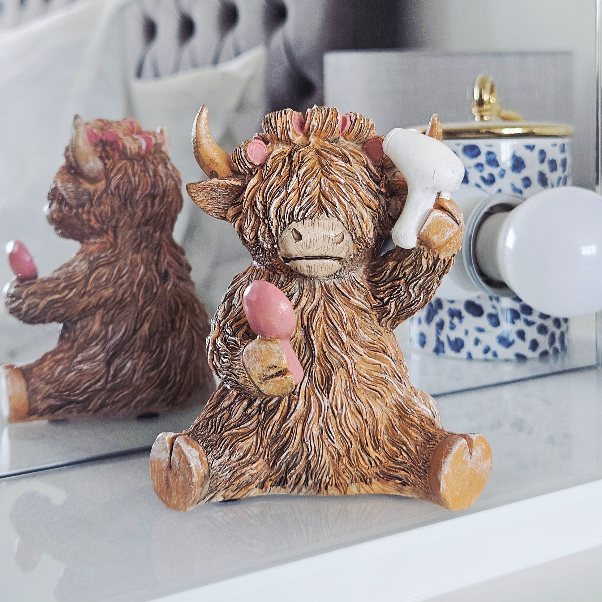 highland cow ornament hairdo with rollers in hair holding hairdryer and brush