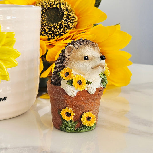 decorative hedgehog small ornament inside a plant pot with sunflowers