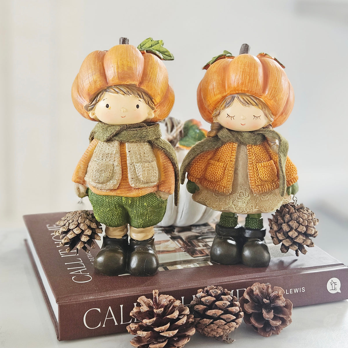 Autumn pumpkin boy and girl figurines with pinecones