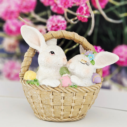 Decorative figurines of two rabbits in a basket with Easter eggs snuggled up