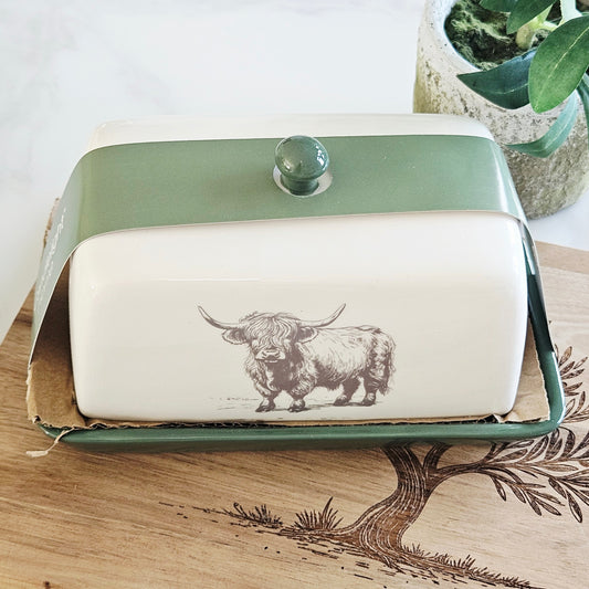 Rectangular ceramic butter dish with green lid and highland illustration on it