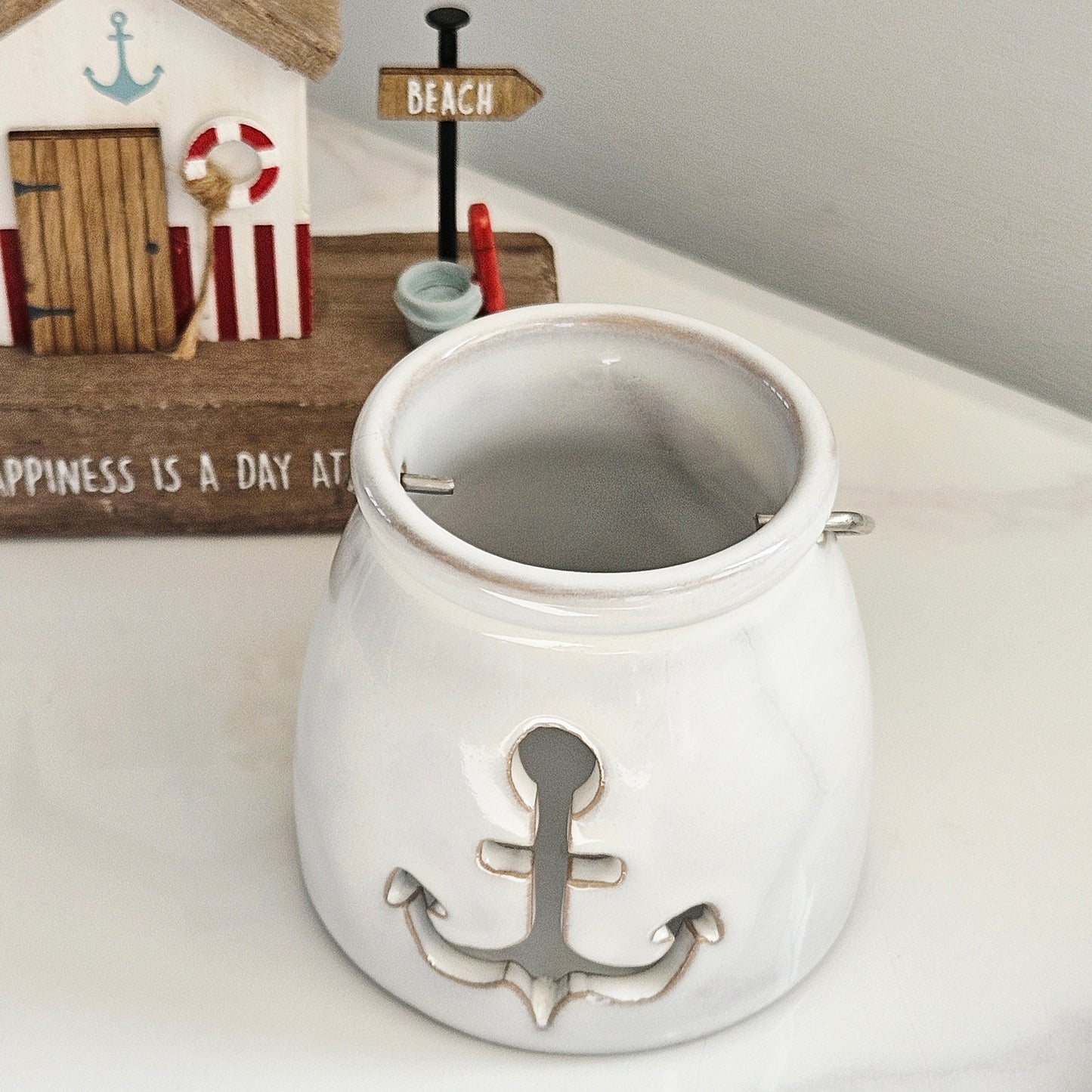 White ceramic candle pot holder with anchor design cut out and metal handle