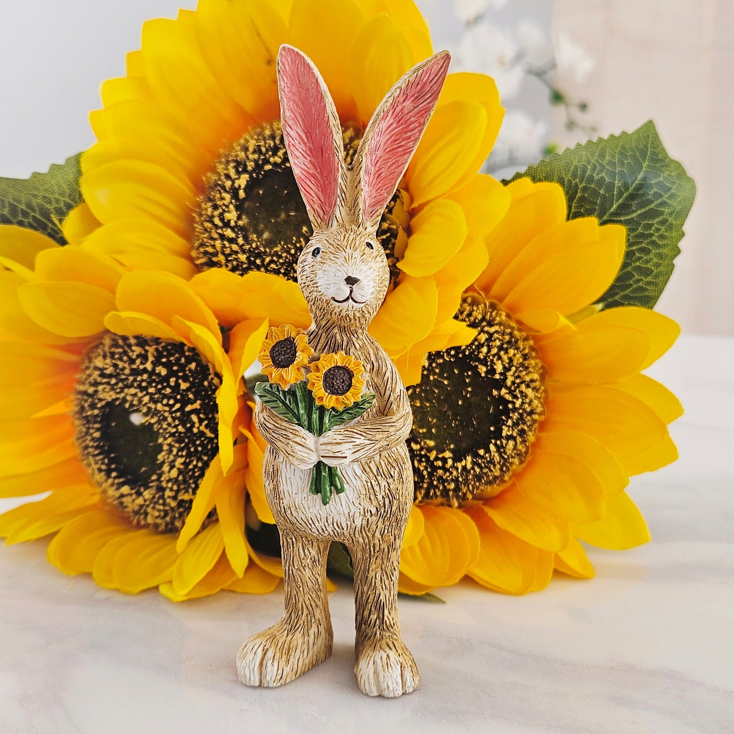 Statue of a jasper rabbit figurine holding sunflowers 