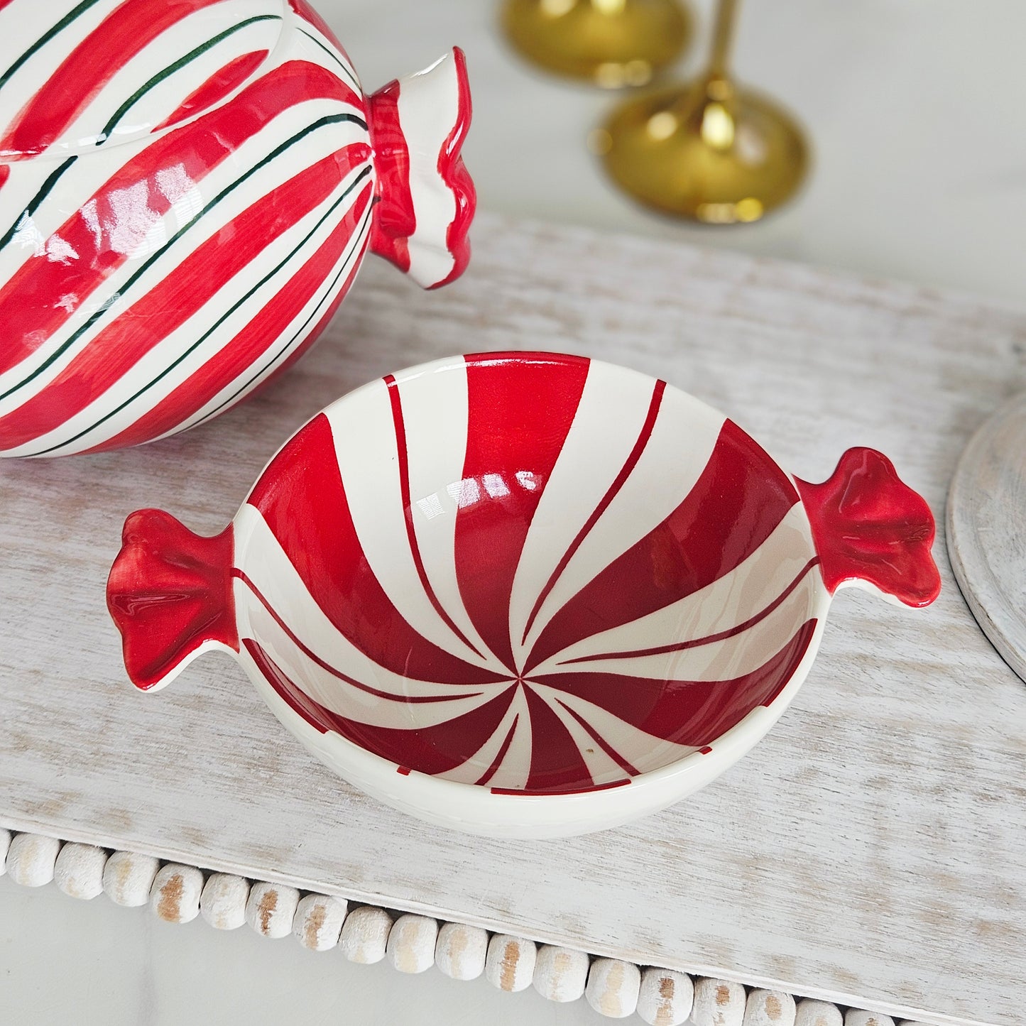 A candy-shaped ceramic bowl with red and white swirls and small side handles, 16cm