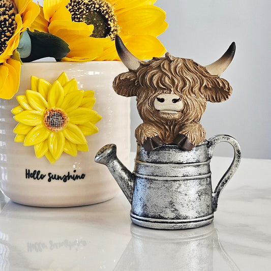 Decorative highland cow sitting in a watering can 