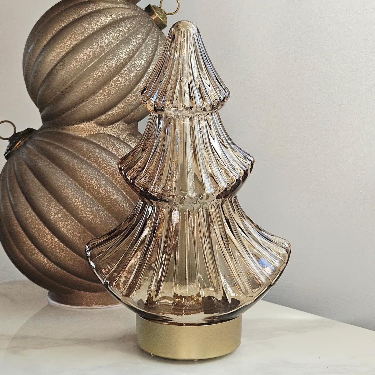 A ribbed, tiered glass led  Christmas tree ornament in a champagne gold finish with a gold base