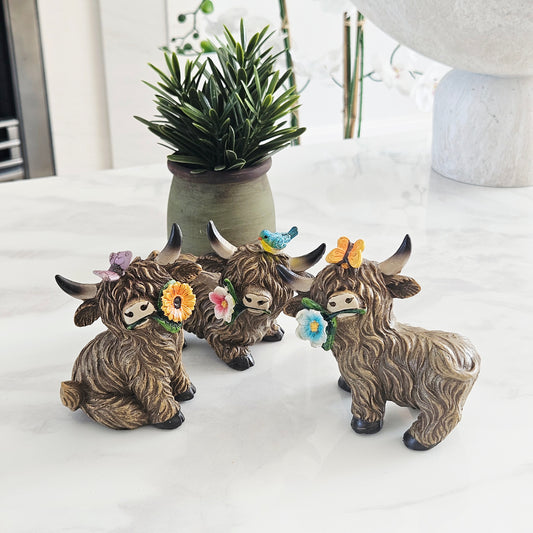highland cow 10cm ornament with butterfly or bird on its head and a colourful flower in its mouth