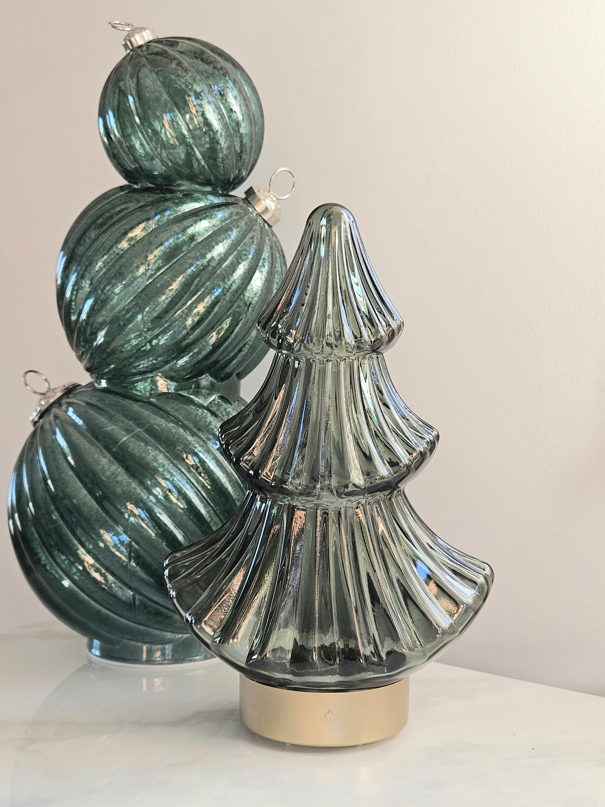 A decorative glass holiday christmas tree led ornament in a ribbed, fluted style with a metallic gold base