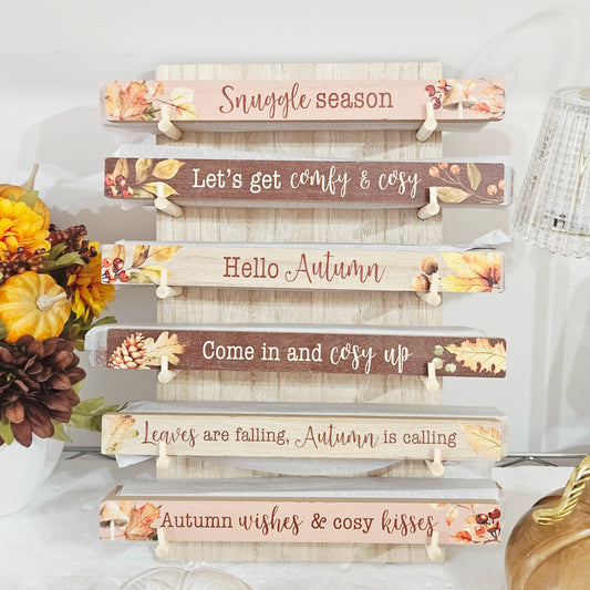 A stack of six rustic wooden sign plaques with autumn-themed quotes and fall foliage designs, 25cm