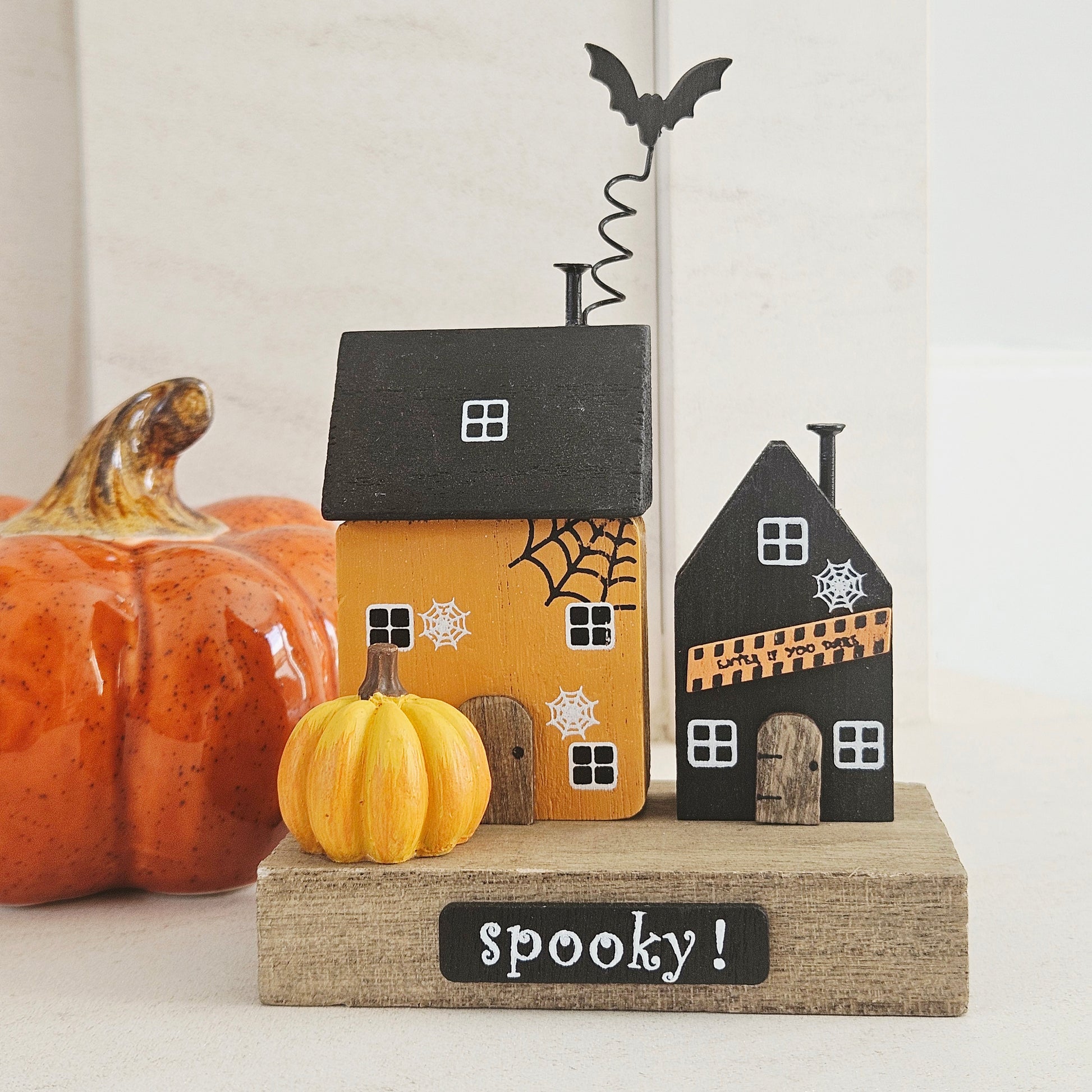 Halloween-themed wooden decorative house set with pumpkins and a bat 